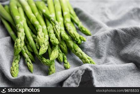 Fresh green asparagus on grey textile background. Flat lay
