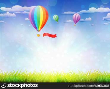 Fresh green grass and hot air balloons in the sky background.. Hot air balloons over grass field