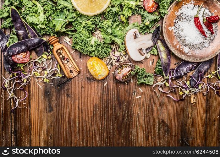 Fresh green kale and vegetables ingredients for cooking on rustic wooden background, top view, border.