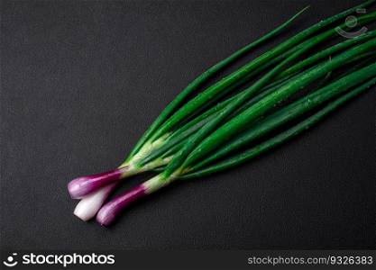 Fresh green onions for cooking a healthy vegetarian dish on a dark concrete background