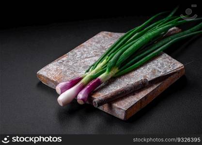 Fresh green onions for cooking a healthy vegetarian dish on a dark concrete background
