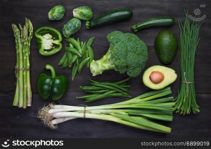 Fresh green organic vegetables on black wooden vintage table.Top view
