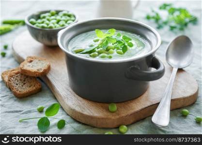 Fresh green pea soup bowl on gray concrete background