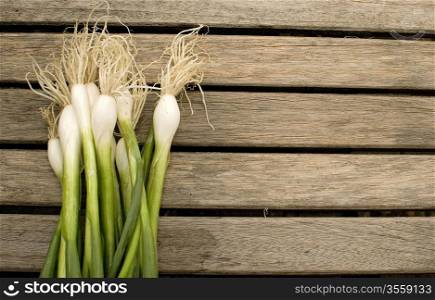 fresh green spring onions over old wooden table