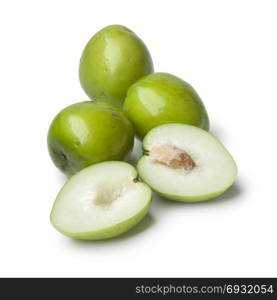 Fresh green whole and half Ambarella fruit with a fibrous pit on white background