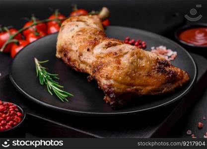 Fresh grilled chicken leg with salt, spices and herbs on a dark concrete background