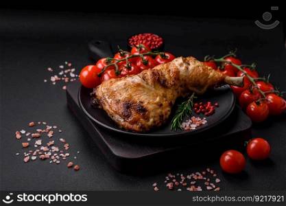 Fresh grilled chicken leg with salt, spices and herbs on a dark concrete background