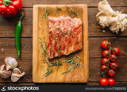 Fresh grilled ribs on wooden table, top view, nobody. Pepper, garlic and herb on background