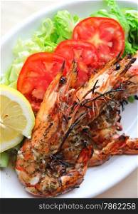 Fresh grilled shrimps with tomatoes, green salad and lemon on white plate