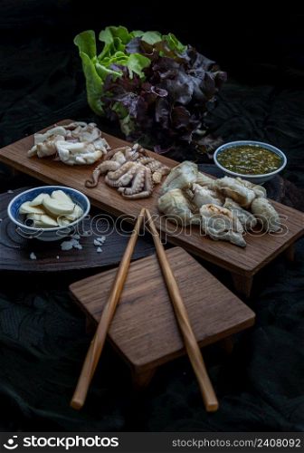 Fresh grilled squid, Octopus tentacles and Squids eggs on Wooden tray Served with Fresh vegetables, Garlic slides and Spicy seafood dipping sauce,.Selective Focus.