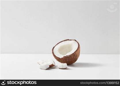 Fresh half of ripe organic tropical coconut fruit on a light grey duotone background with soft shadows and copy space. Vegetarian concept.. Half of fresh ripe tropical coconut fruit on a light grey background.