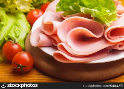 Fresh ham slices with lattuce and cherry tomato on the wooden board