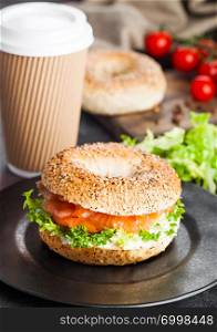 Fresh healthy bagel sandwich with salmon, ricotta and soft egg on vintage chopping board on white kitchen table background