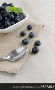 Fresh healthy blueberries in small bowl on wood table