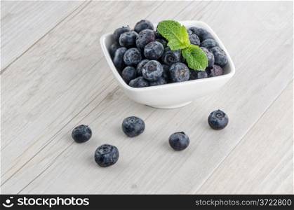 Fresh healthy blueberries in small bowl on wood table
