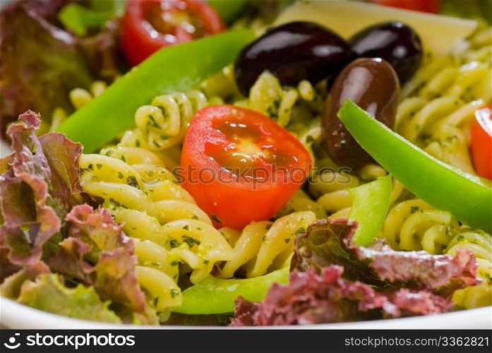 fresh healthy homemade italian fusilli pasta salad with parmesan cheese,pachino cherry tomatoes, black olives and mix vegetables ,dressed with extra-virgin olive oil and pesto sauce