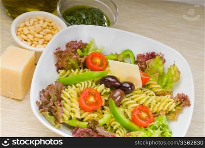 fresh healthy homemade italian fusilli pasta salad with parmesan cheese,pachino cherry tomatoes, black olives and mix vegetables ,dressed with extra-virgin olive oil and pesto sauce