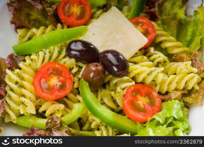 fresh healthy homemade italian fusilli pasta salad with parmesan cheese,pachino cherry tomatoes, black olives and mix vegetables ,dressed with extra-virgin olive oil and pesto sauce