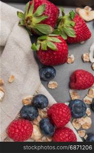 Fresh healthy ingredients for breakfast or smoothie on dark vintage board. Blueberries, raspberries and strawberries. Summer and healthy food concept.
