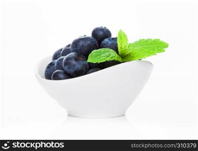 Fresh healthy organic blueberry in white bowl with mint leaf on white background