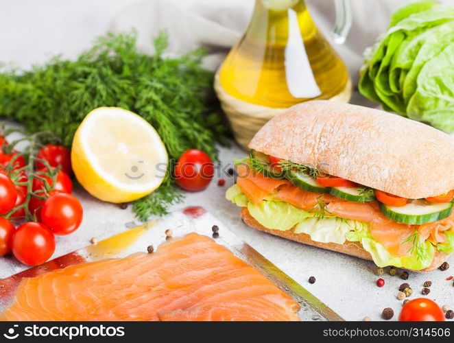 Fresh healthy salmon sandwich with lettuce and cucumber on the plate on stone background. Breakfast snack. Fresh tomatoes, dill and lemon.