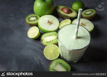 Fresh healthy smoothie in a glass and green fruits on a greyish kitchen table. Dieting context. Vegetarian food. Detox concept. Copy space.