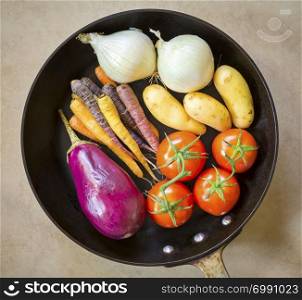 Fresh healthy vegetables ready for roasting in a deep black pan
