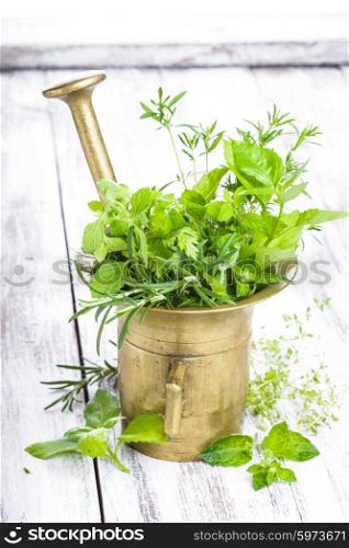 Fresh herbs in the copper mortar on the shabby wooden table. Fresh herbs