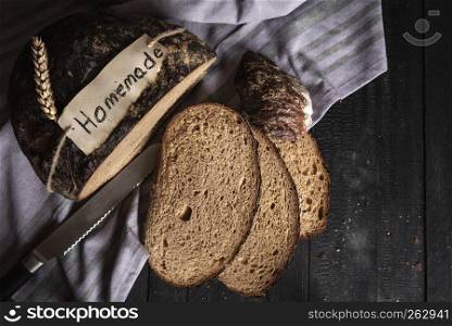 Fresh home-baked rye bread above view on a rustic wooden table. Slices of brown healthy bread on the kitchen towel