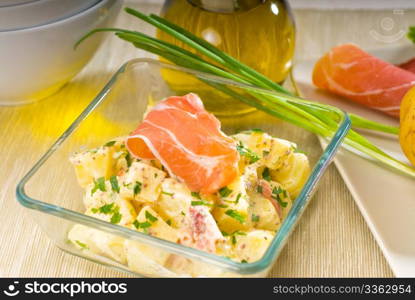 fresh home made parma ham and potato salad,with raw ingredients around with bowls and dishware on a table