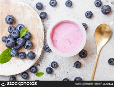 Fresh homemade blueberry yogurt with fresh berries on wooden board and golden spoon. Top view