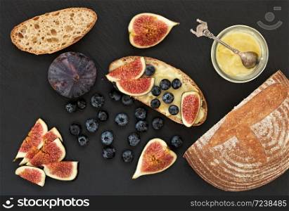 Fresh homemade bread, homemade baking. Blank for sandwich, figs, blueberries, sauce. Top view. Black stone background.