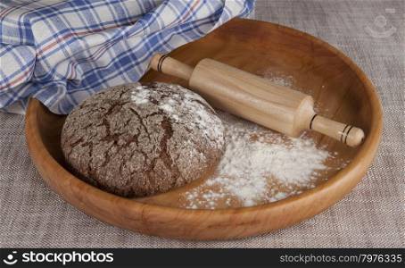 Fresh homemade bread made from durum wheat, rye, on a wooden tray with a rolling pin. Composition on a beautiful tablecloths canvas. Photos for magazines about cooking, confectionery, cooking.