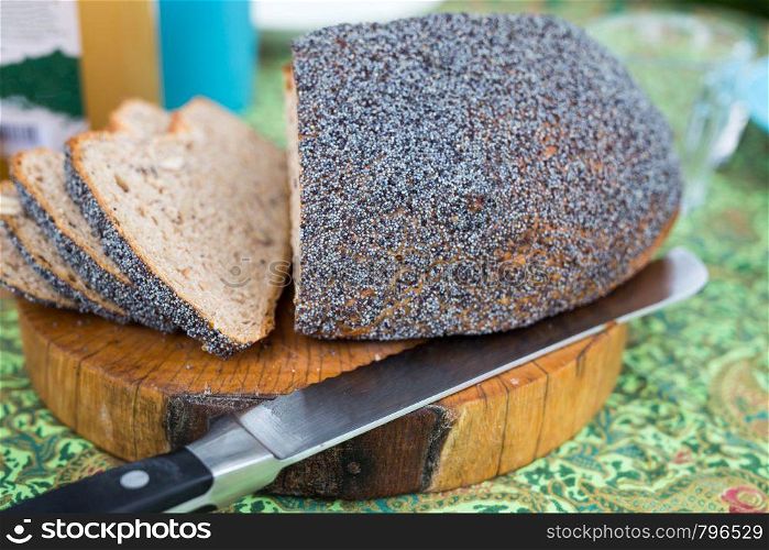 Fresh homemade bread on cutting board with knife on colorful breakfast table close-up. Fresh homemade bread on cutting board with knife on colorful breakfast table