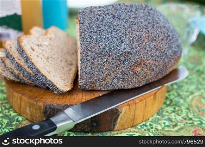 Fresh homemade bread on cutting board with knife on colorful breakfast table close-up. Fresh homemade bread on cutting board with knife on colorful breakfast table