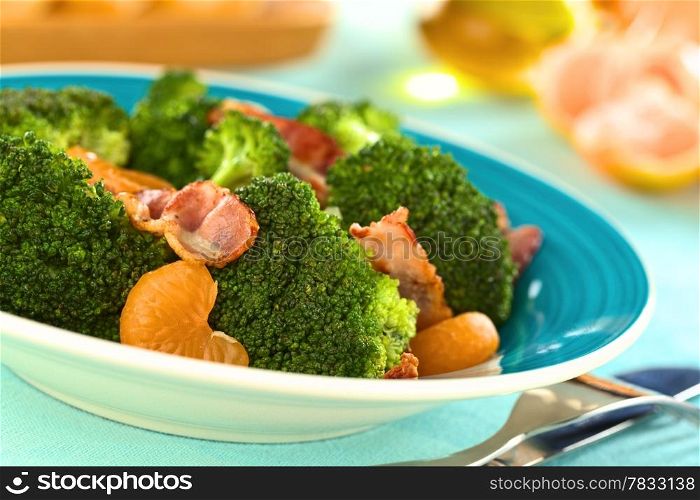 Fresh homemade broccoli, mandarin and bacon salad on blue plate (Selective Focus, Focus on the broccoli and the mandarin in the front)