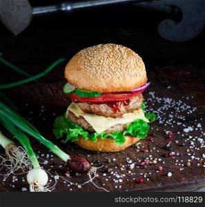 fresh homemade burger with lettuce, cheese, onion and tomato on a rustic wooden board. fresh homemade burger with lettuce, cheese, onion and tomato