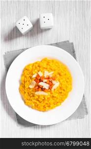 Fresh homemade carrot risotto made with pureed carrot, garnished with roasted carrot and hard cheese, photographed overhead with natural light (Selective Focus, Focus on the top of the risotto)