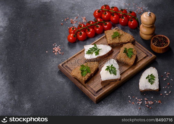 Fresh homemade chicken liver pate on bread over grey background. Appetizer, baguette with liver paste and herbs, closeup. Homemade breakfast