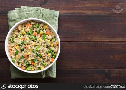 Fresh homemade cooked white quinoa with colorful vegetables (green peas, sweet corn kernels, green beans, carrots) and parsley in bowl, photographed overhead with copy space on the right side. Quinoa with Vegetables