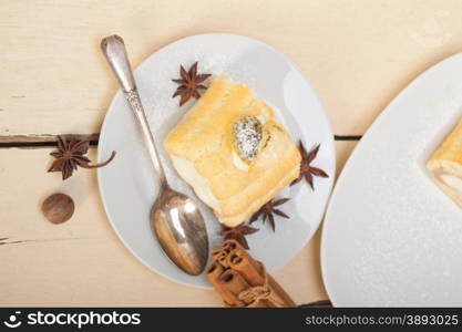 fresh homemade cream roll cake dessert and spices over white rustic wood table