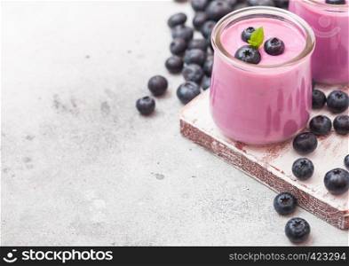Fresh homemade creamy blueberry yoghurt with fresh blueberries on vintage wooden board on stone table background