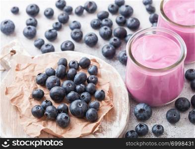 Fresh homemade creamy blueberry yoghurt with fresh blueberries on vintage wooden board on stone table background
