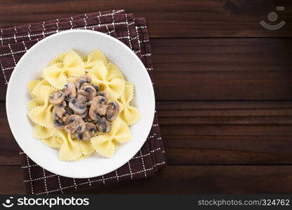 Fresh homemade creamy vegetarian mushroom sauce on farfalle pasta served in bowl, copy space on the side, photographed overhead on dark wood. Creamy Mushroom Sauce on Pasta