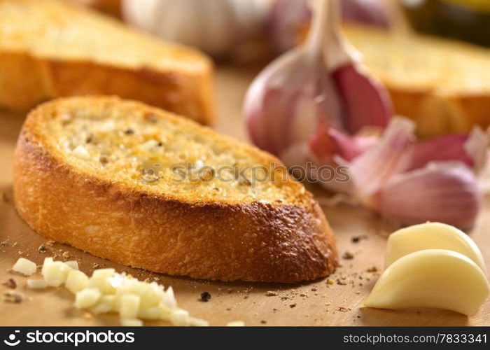 Fresh homemade Italian antipasto called Bruschetta with garlic, olive oil, salt and ground pepper on wooden board (Selective Focus, Focus on the right front edge of the first bruschetta)