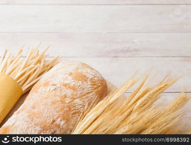 Fresh homemade italian bread with raw wheat and spaghetti on wood background.