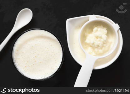 Fresh homemade kefir drink in glass with kefir grains in strainer in bowl on the side, photographed overhead on slate with natural light (Selective Focus, Focus on the kefir drink). Kefir Drink