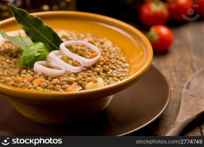 fresh homemade lentils soup with onions and cherry tomatoes on wooden table