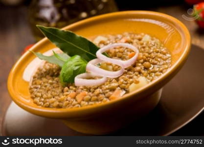 fresh homemade lentils soup with onions and cherry tomatoes on wooden table