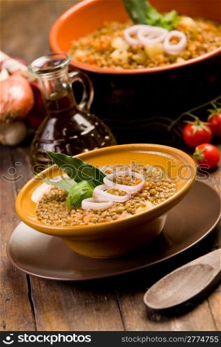 fresh homemade lentils soup with onions and cherry tomatoes on wooden table